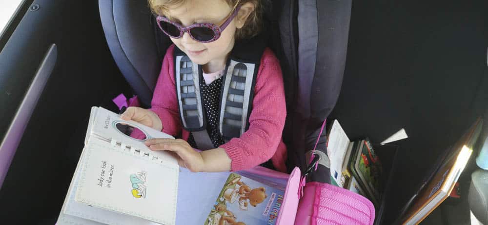 Kind schaut im Auto Bücher an