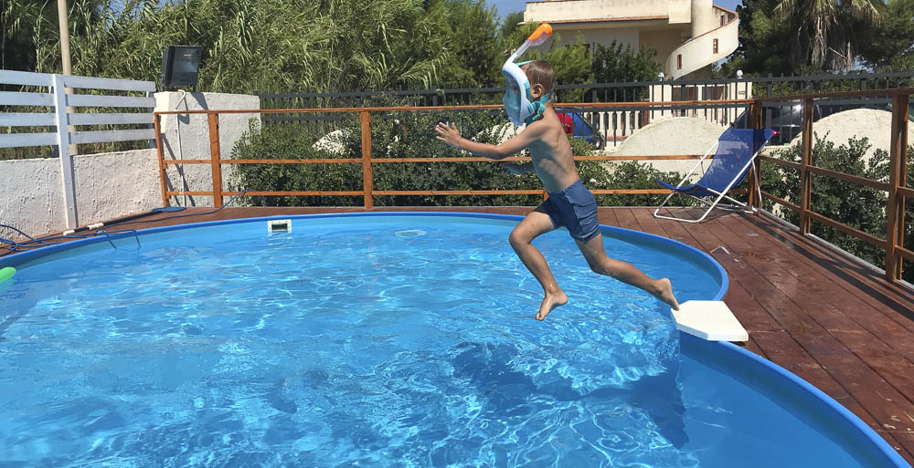 Kind springt in Pool mit Schnorchelmaske